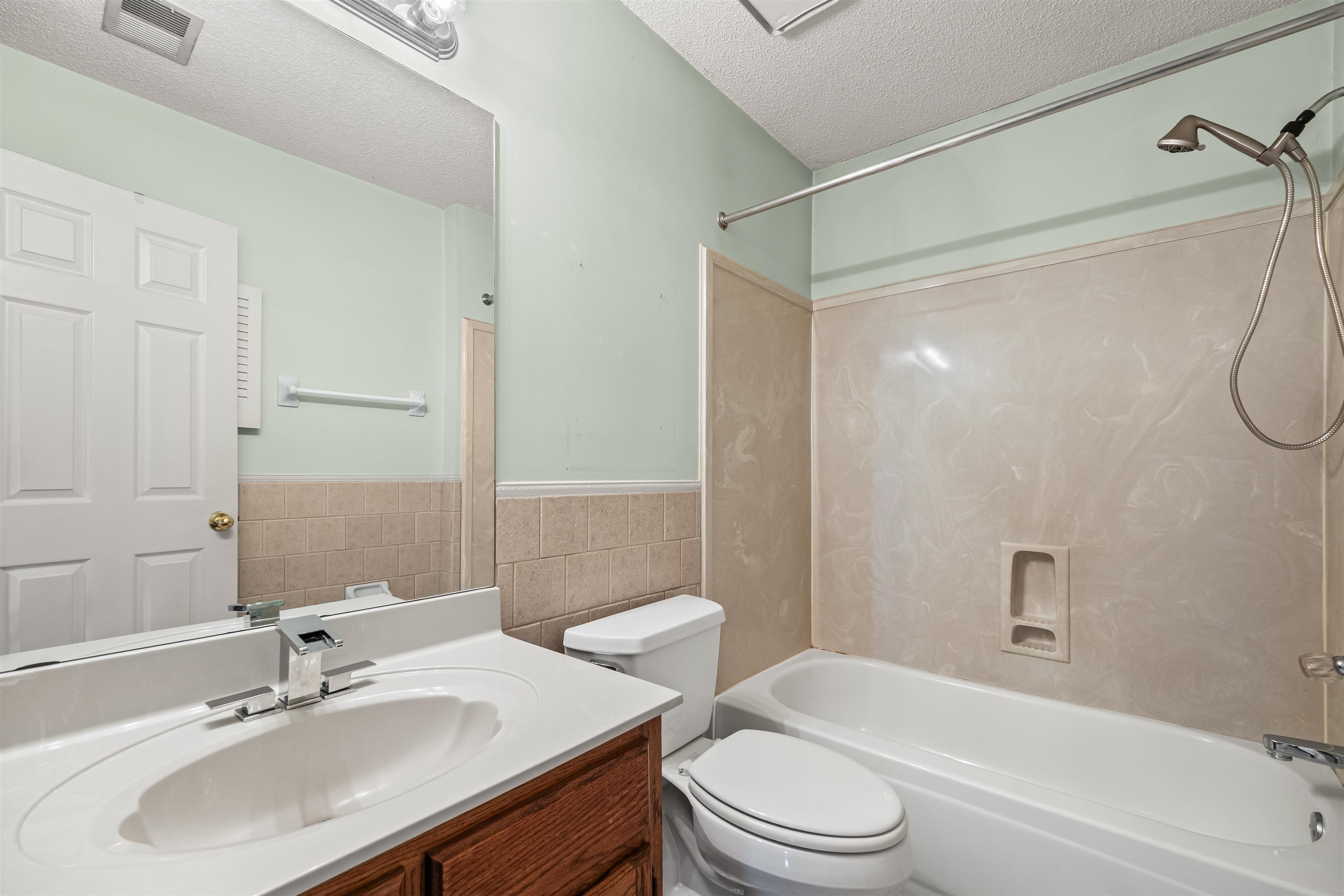 8645 Bazemore Road Memphis, TN 38018 - Photo 22 of 28 Bathroom featuring a textured ceiling, tile walls, bathtub / shower combination, vanity, and wainscoting