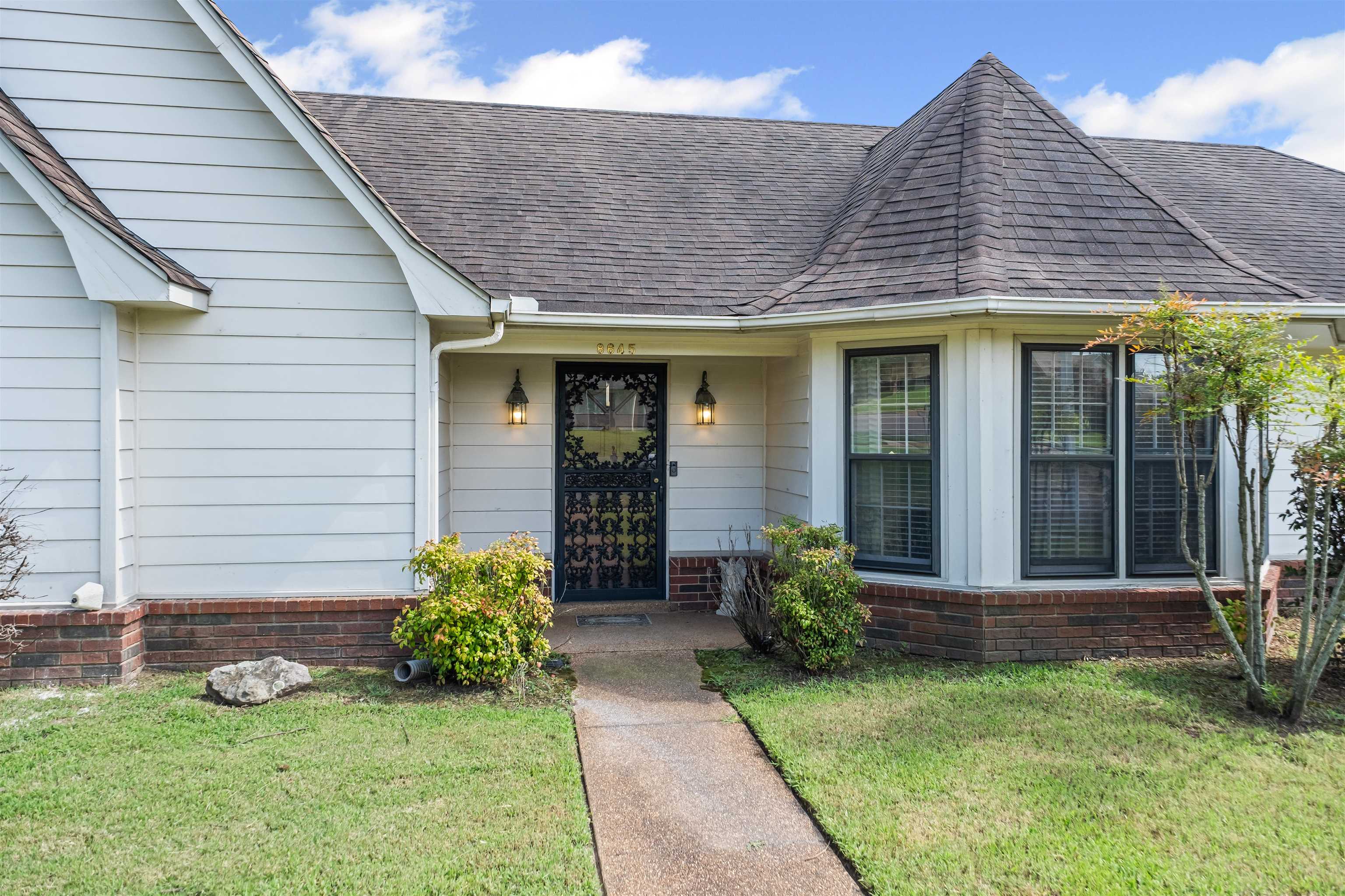 8645 Bazemore Road Memphis, TN 38018 - Photo 26 of 28 Doorway to property with a shingled roof, brick siding, and a lawn