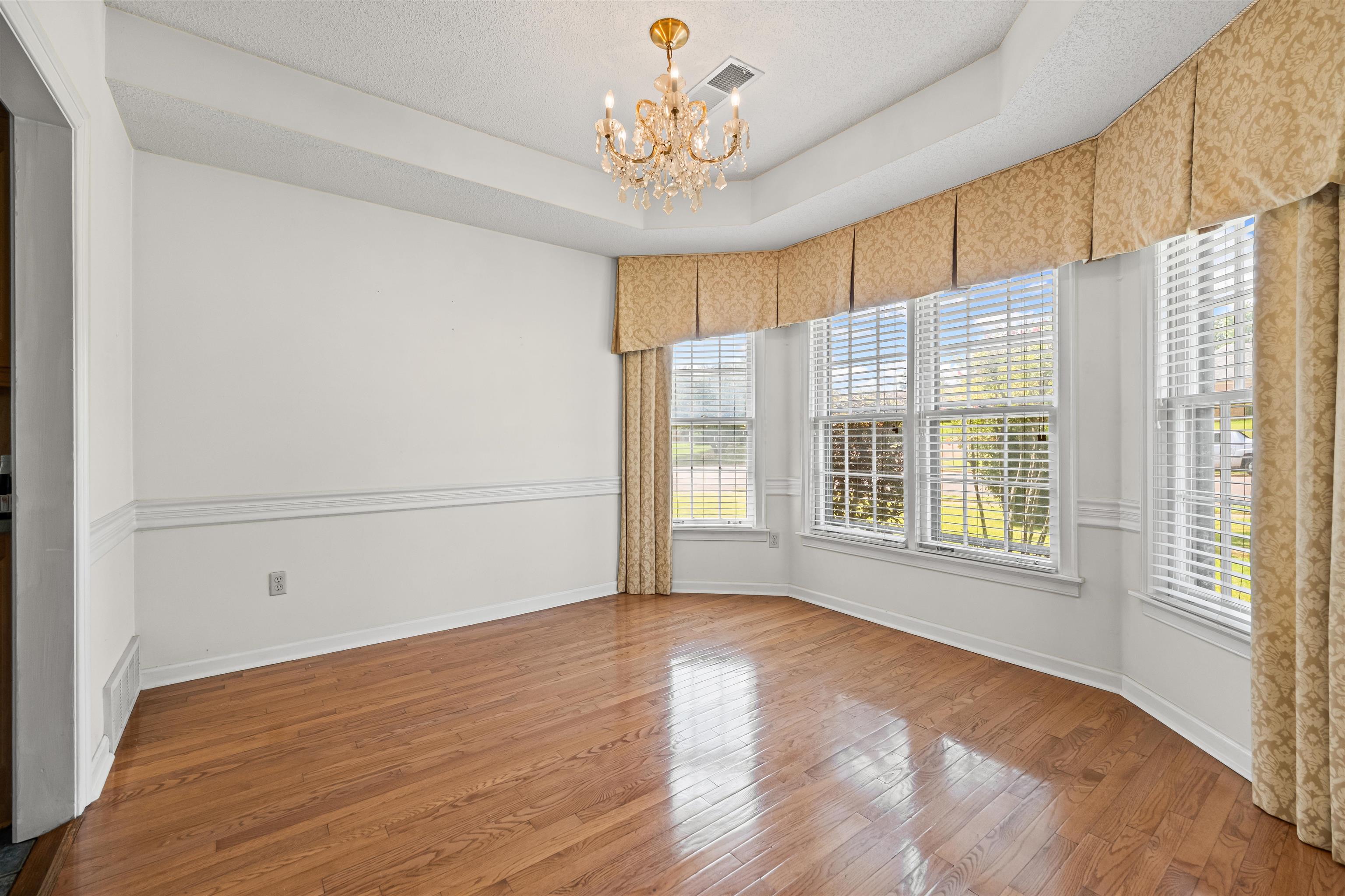 8645 Bazemore Road Memphis, TN 38018 - Photo 5 of 28 Empty room featuring a chandelier, wood finished floors, a raised ceiling, and a textured ceiling