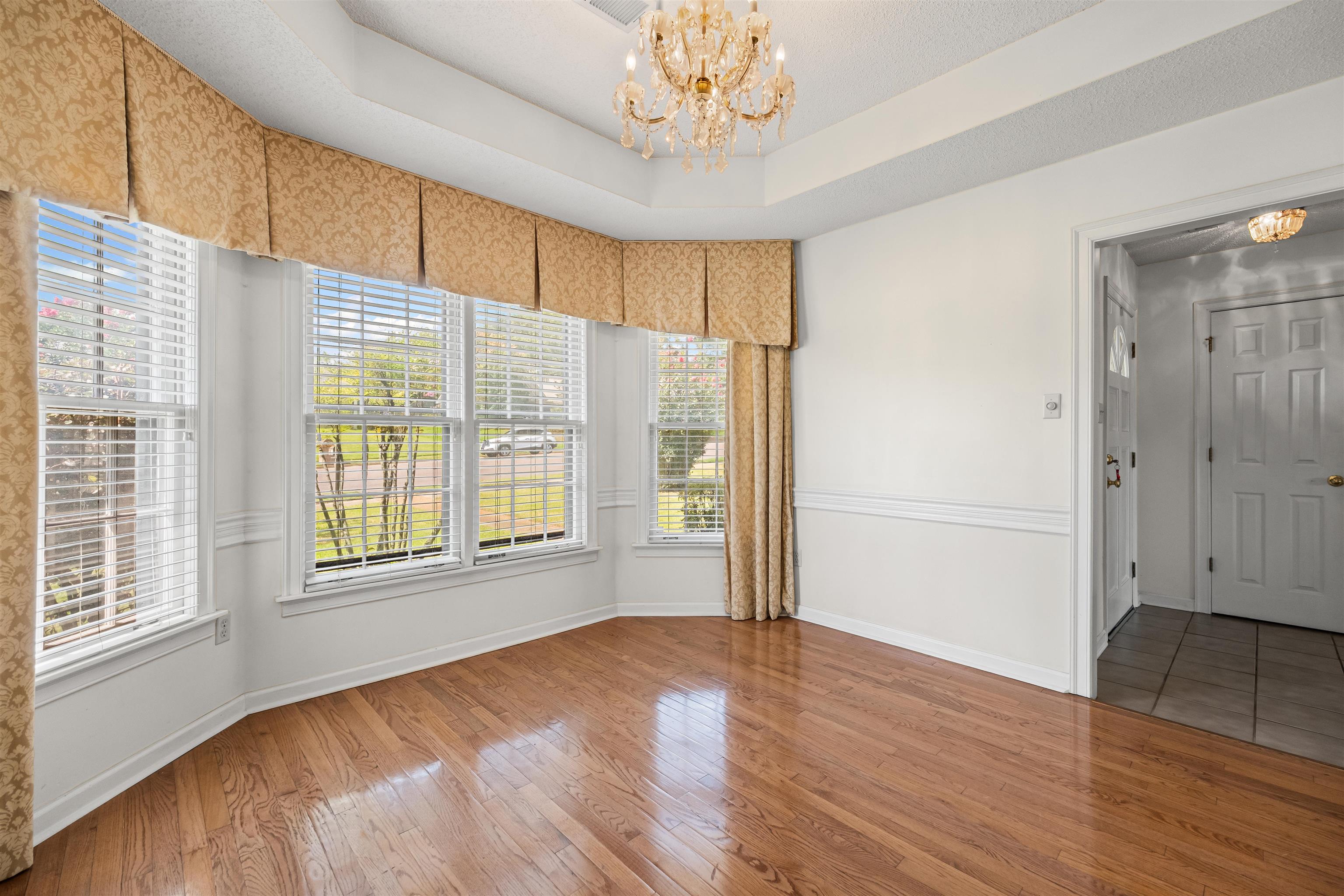 8645 Bazemore Road Memphis, TN 38018 - Photo 6 of 28 Unfurnished room with a chandelier, wood finished floors, and a tray ceiling