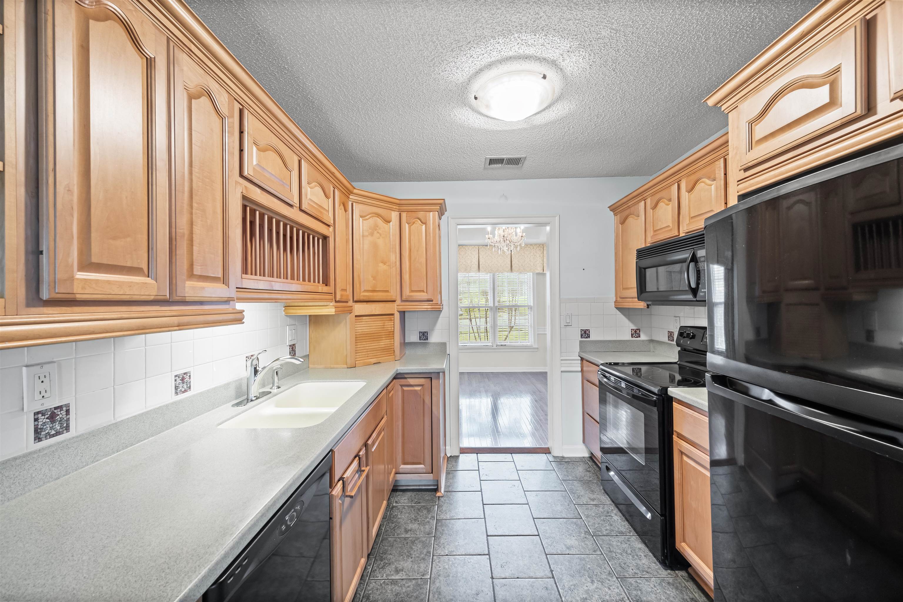 8645 Bazemore Road Memphis, TN 38018 - Photo 7 of 28 Kitchen featuring black appliances, light countertops, tasteful backsplash, and a textured ceiling
