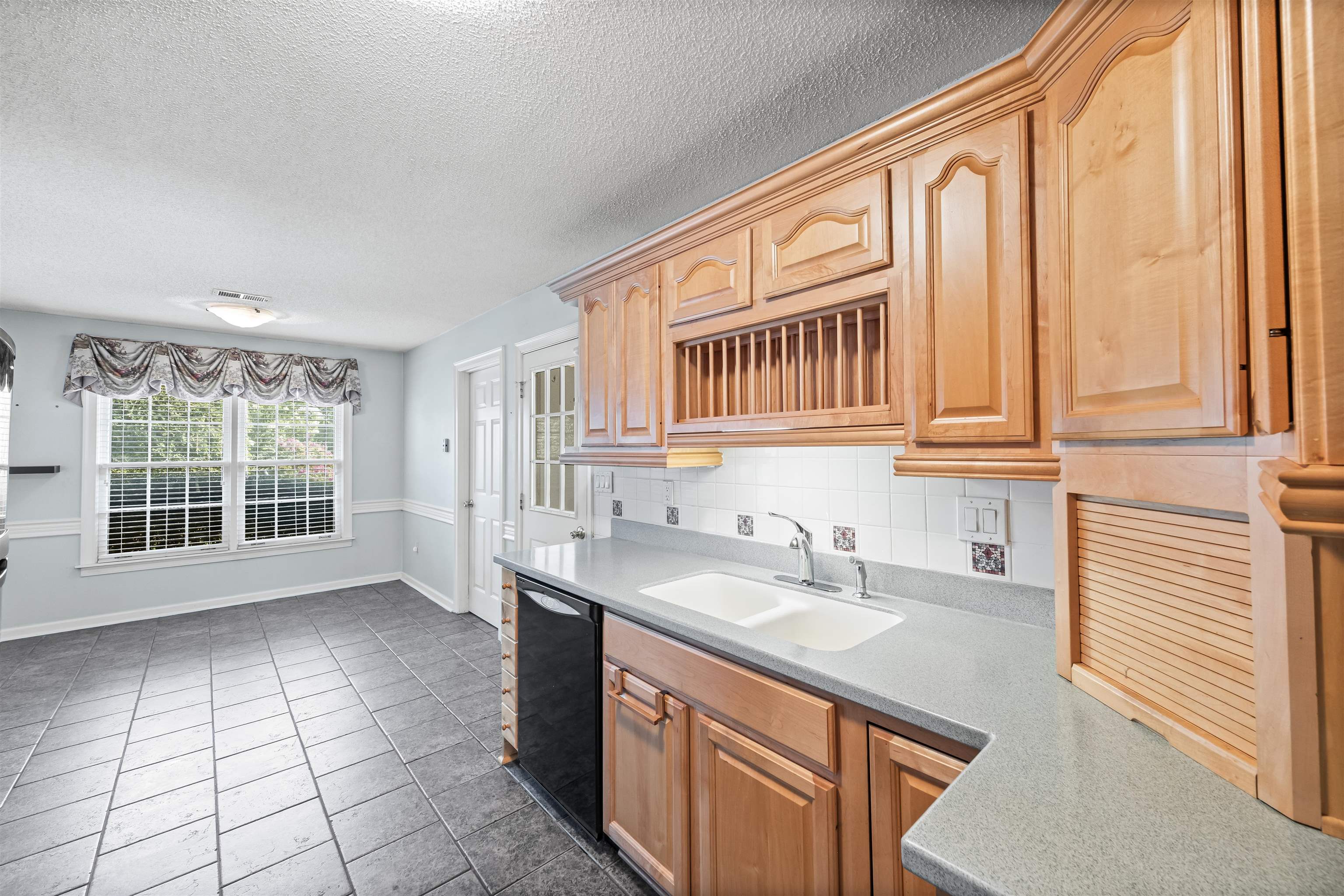 8645 Bazemore Road Memphis, TN 38018 - Photo 10 of 28 Kitchen featuring black dishwasher, light countertops, dark tile patterned flooring, a textured ceiling, and backsplash