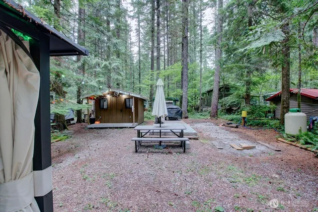 a backyard of a house with table and chairs under an umbrella