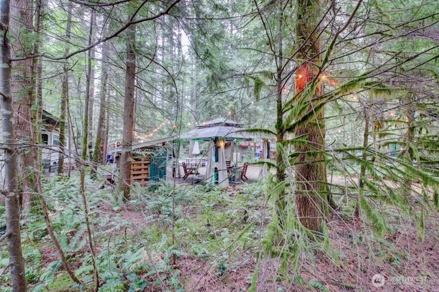 a backyard of a house with table and chairs under an umbrella