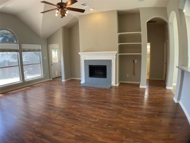 wooden floor fireplace and windows in an empty room