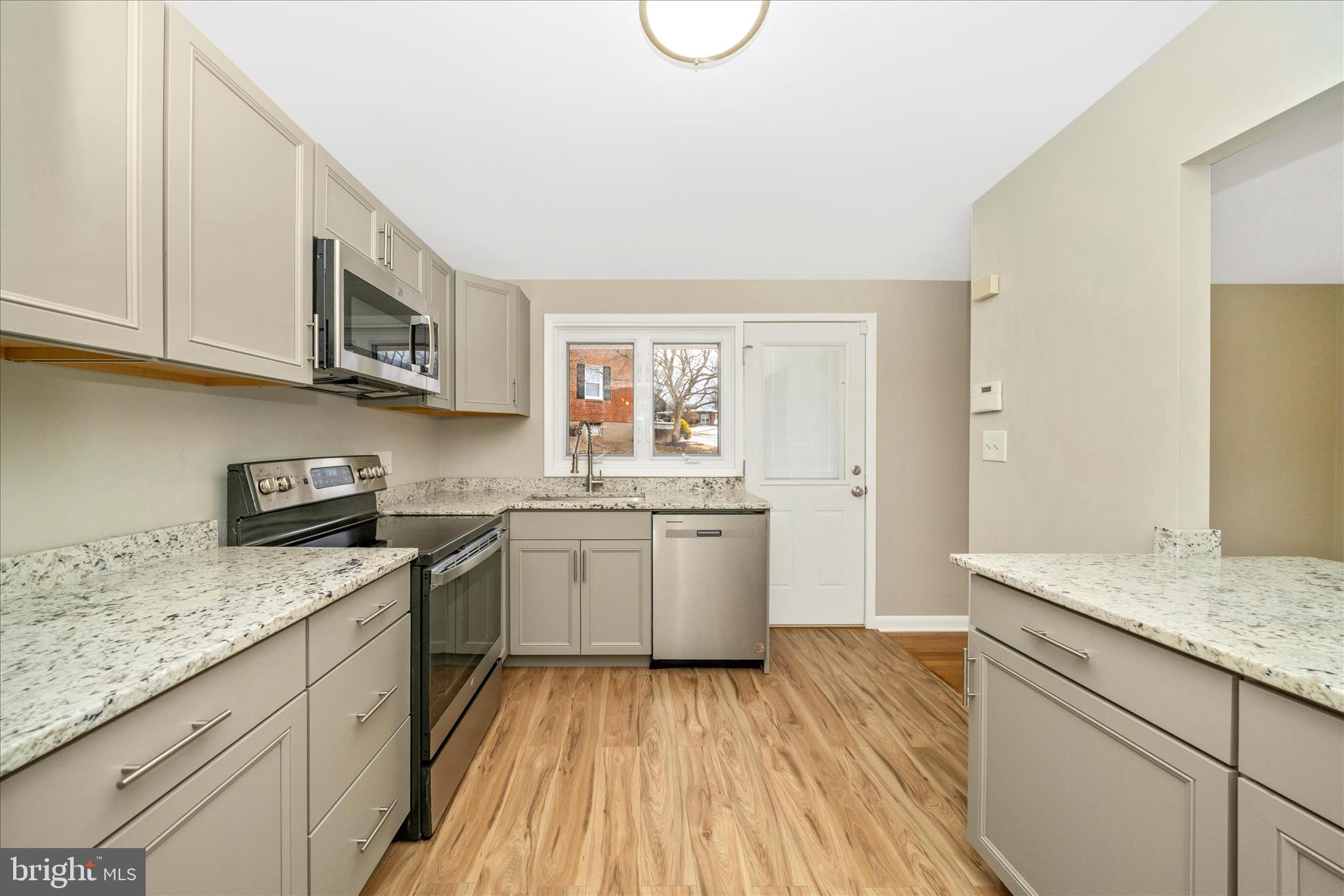 1302 Glenmont Road Baltimore, MD 21239 - Photo 16 of 49 a kitchen with granite countertop a sink cabinets stainless steel appliances and a counter space