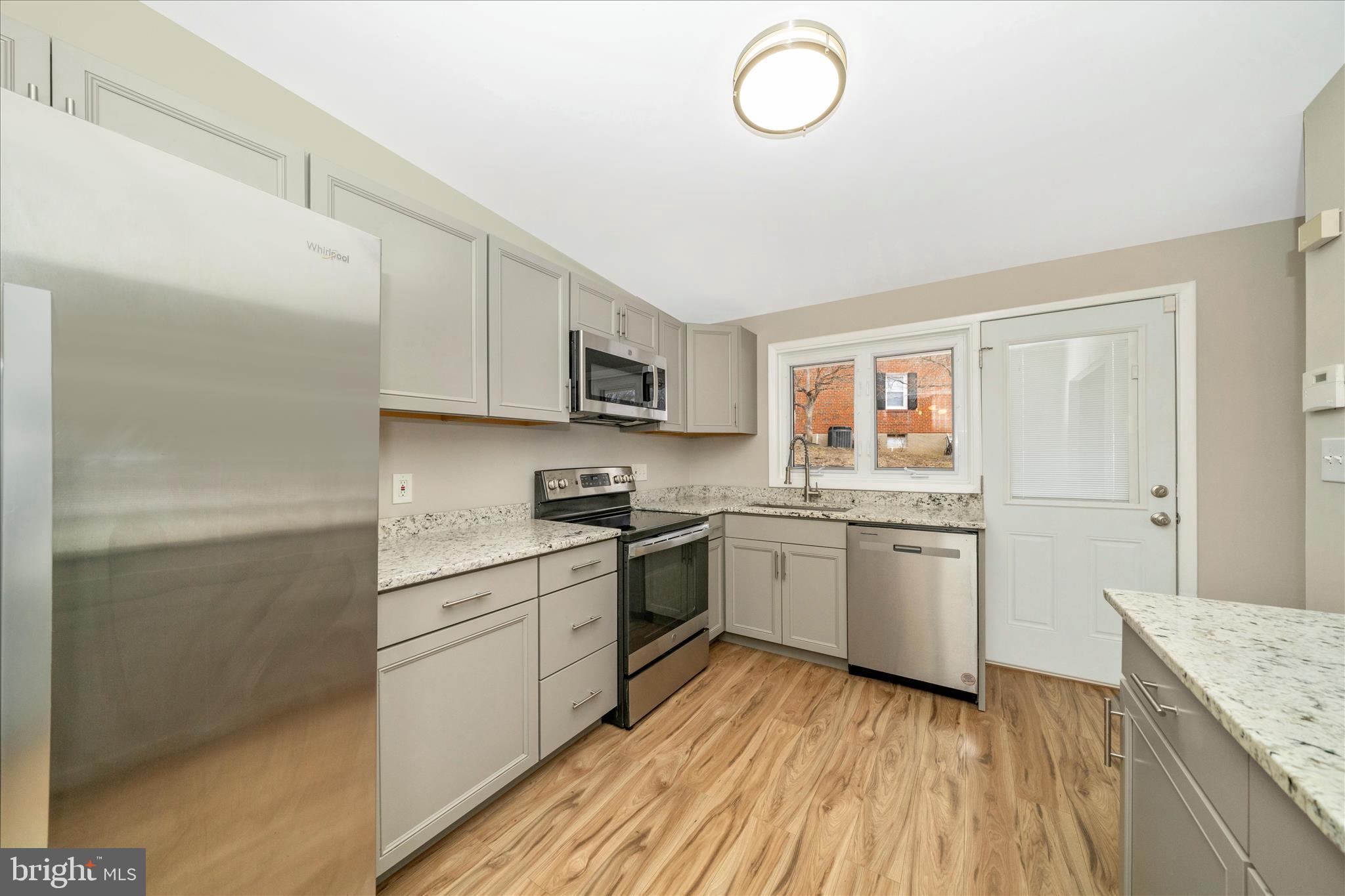 1302 Glenmont Road Baltimore, MD 21239 - Photo 18 of 49 a kitchen with granite countertop a sink cabinets stainless steel appliances and a counter space