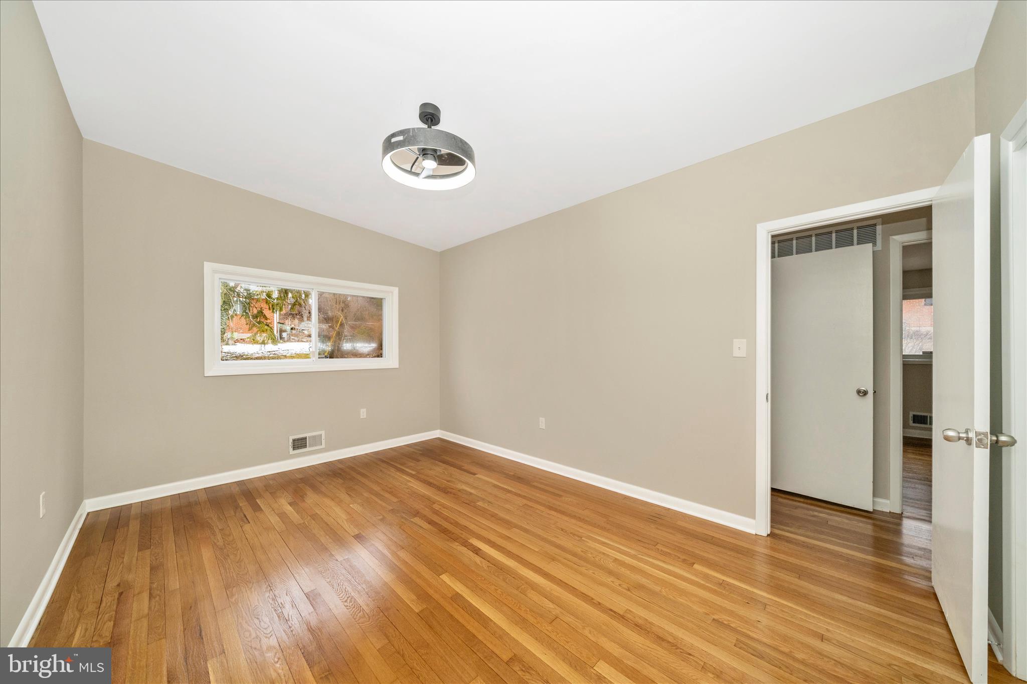 1302 Glenmont Road Baltimore, MD 21239 - Photo 22 of 49 an empty room with wooden floor and windows