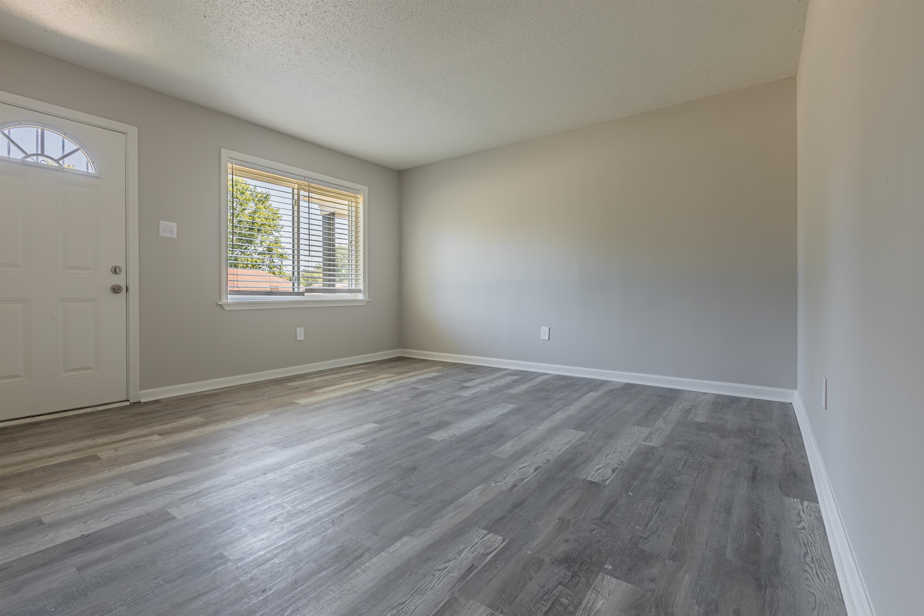 4951 Rosefield Road Memphis, TN 38118 - Photo 4 of 20 an empty room with wooden floor and windows