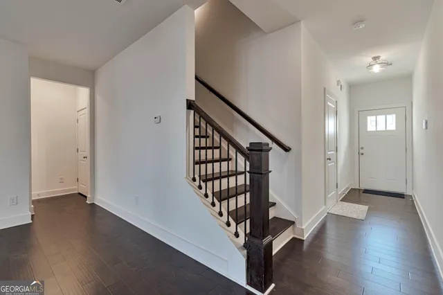 a view of an empty room with wooden floor and a kitchen