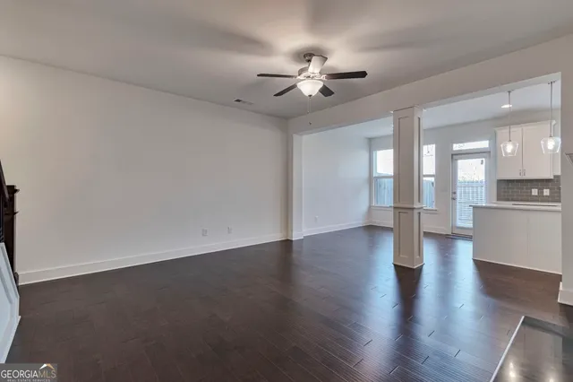 a kitchen with kitchen island granite countertop a refrigerator a sink dishwasher a stove and white cabinets with wooden floor