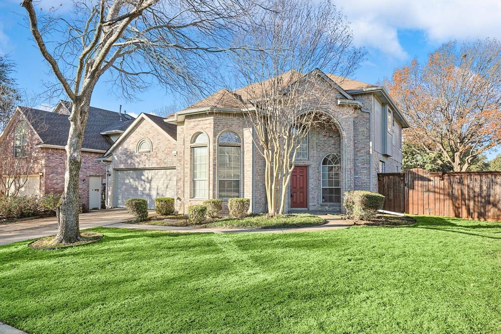 View of front of house featuring brick siding, fence, concrete driveway, a front yard, and a garage