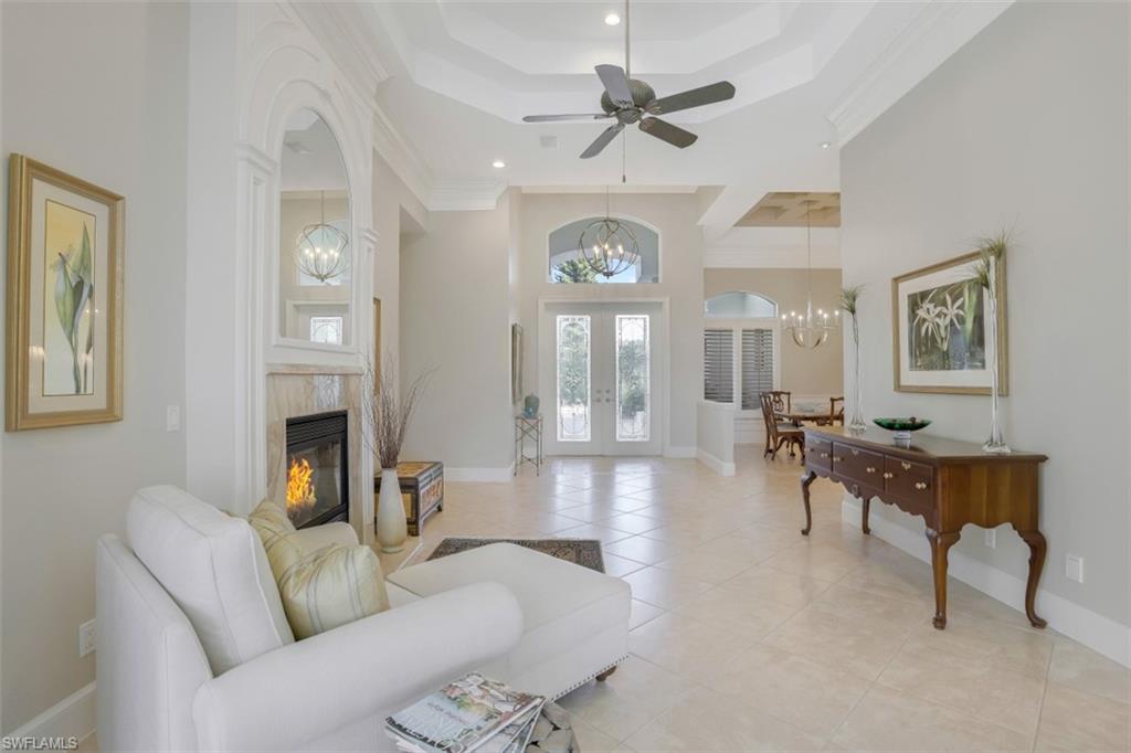 183 Audubon Boulevard Naples, FL 34110 - Photo 10 of 35 a living room with furniture a fireplace and a chandelier