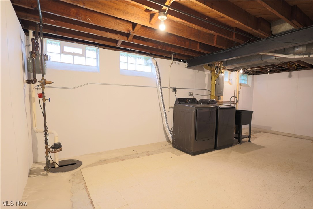 1332 South Green Road South Euclid, OH 44121 - Photo 20 of 23 Basement with electric panel, plenty of natural light, washing machine and clothes dryer, and drainage system