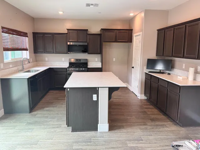 a kitchen with stainless steel appliances wooden cabinets granite counter tops a stove a sink and a wooden floors