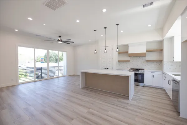 a large white kitchen with wooden floors and stainless steel appliances