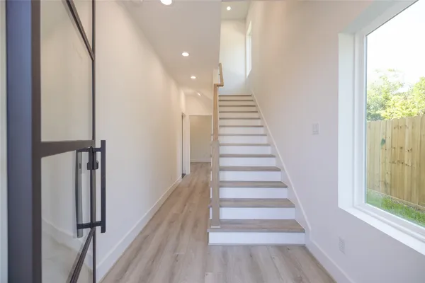 a view of a hallway with wooden floor and windows