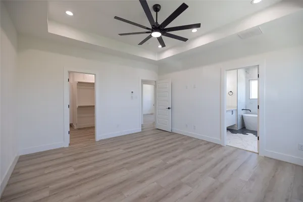 a view of a livingroom with a chandelier fan and wooden floor