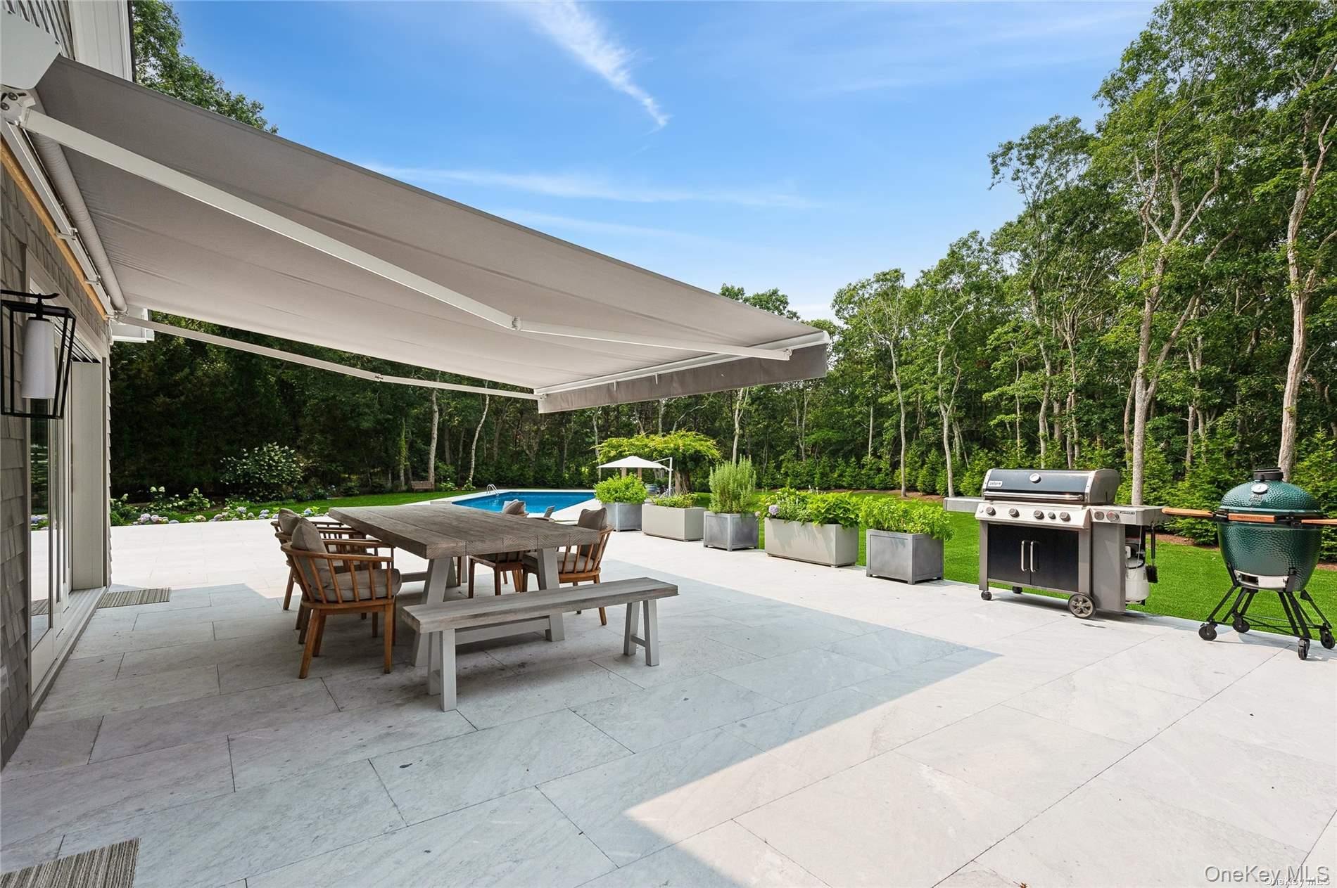 28 Old Meeting House Road Quogue, NY 11959 - Photo 27 of 34 a view of a patio with table and chairs potted plants with wooden fence