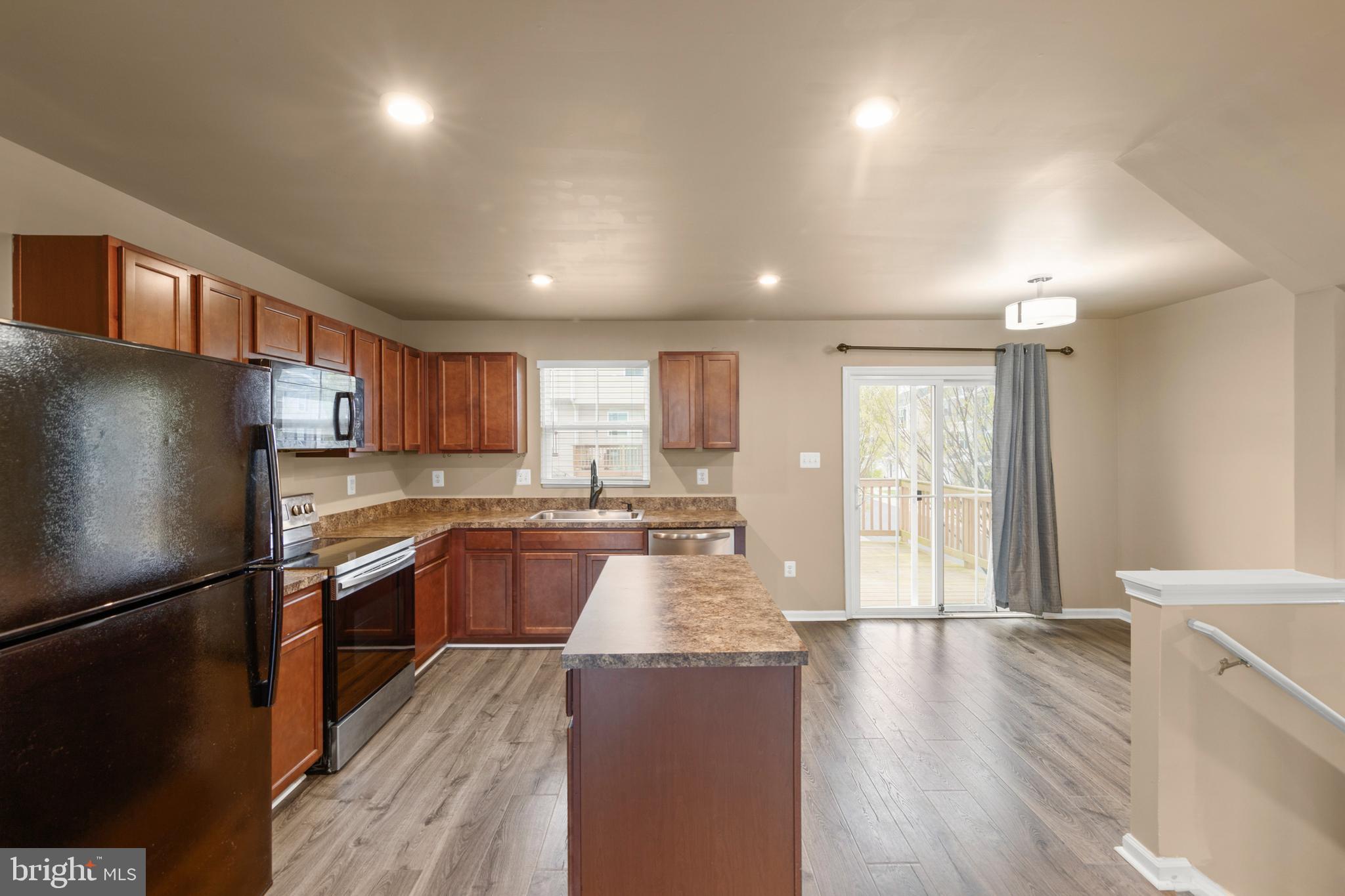 113 Reign Way Winchester, VA 22603 - Photo 2 of 35 a large kitchen with stainless steel appliances granite countertop a refrigerator a sink dishwasher a stove and a dining table with wooden floor