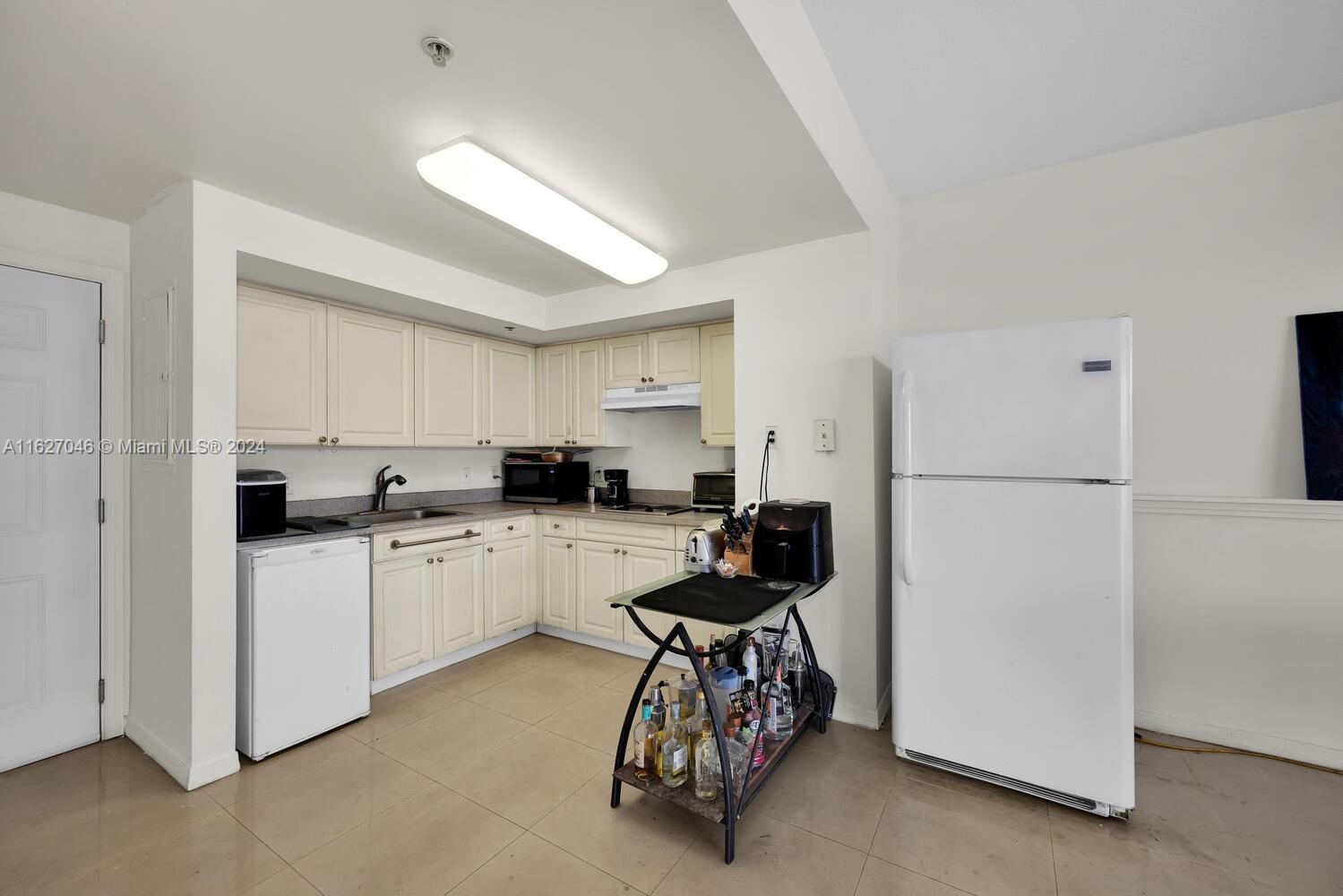 West Flagler Miami, FL 33125 - Photo 13 of 29 a kitchen with sink a refrigerator and white cabinets