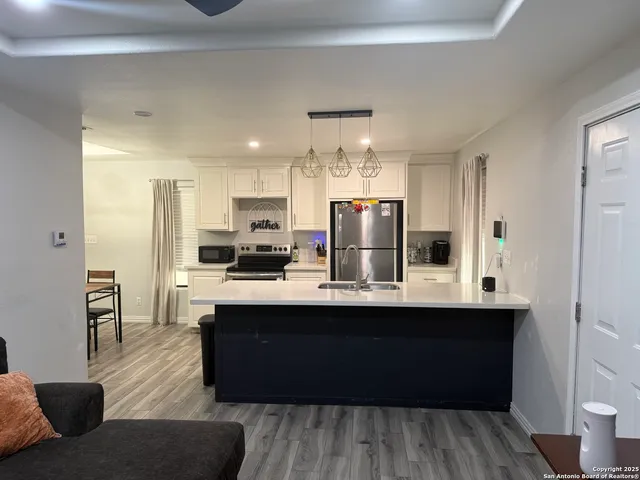 a kitchen with stainless steel appliances kitchen island granite countertop a sink refrigerator and cabinets