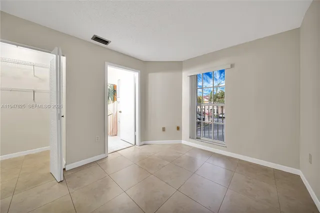 a view of an empty room with window and closet area