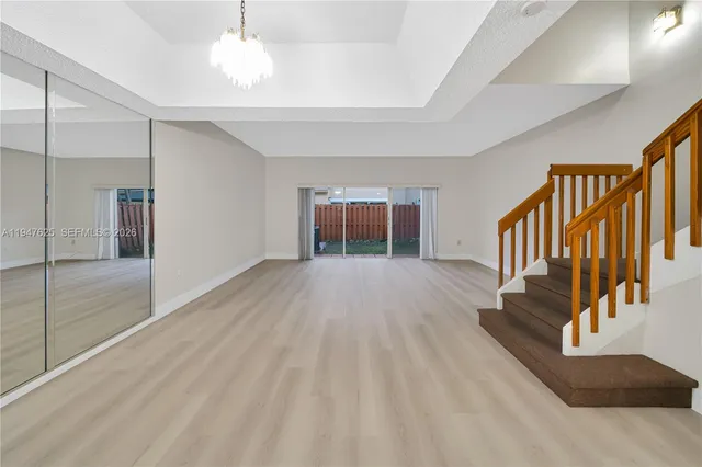 a view of an empty room with window and stairs