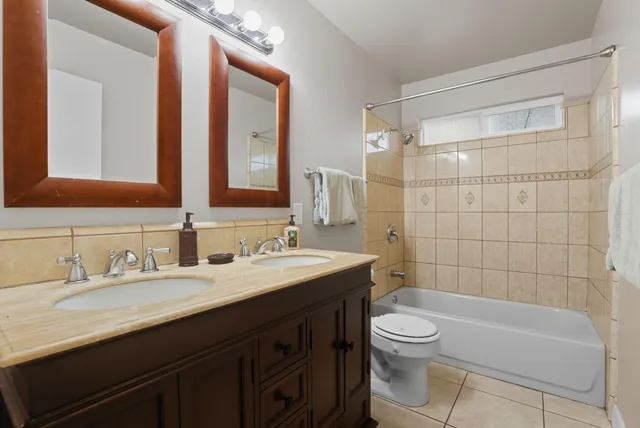 a bathroom with a double vanity sink toilet mirror and shower