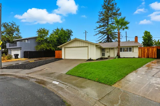 a view of a house with a yard and large tree