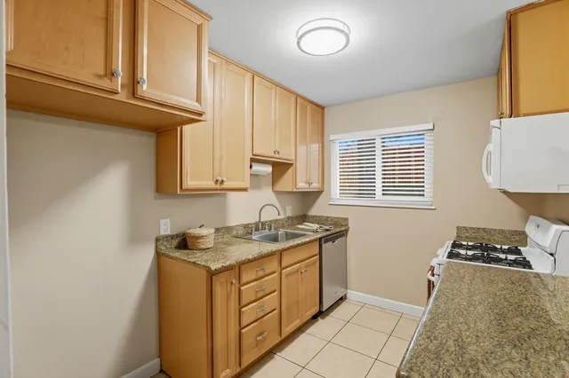 a kitchen with granite countertop a stove sink and cabinets