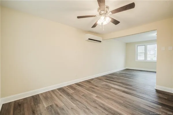 an empty room with wooden floor fan and windows
