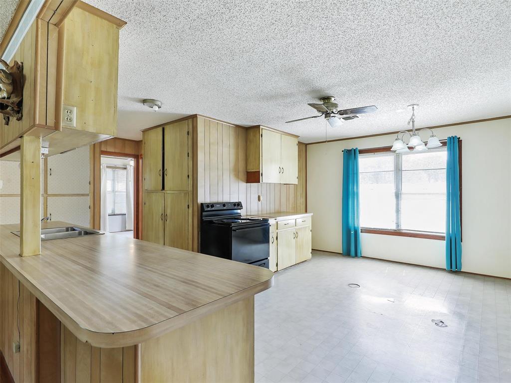 404 Selma Road Bowie, TX 76230 - Photo 11 of 21 a kitchen with stainless steel appliances kitchen island granite countertop a refrigerator a sink and dishwasher with a dining table