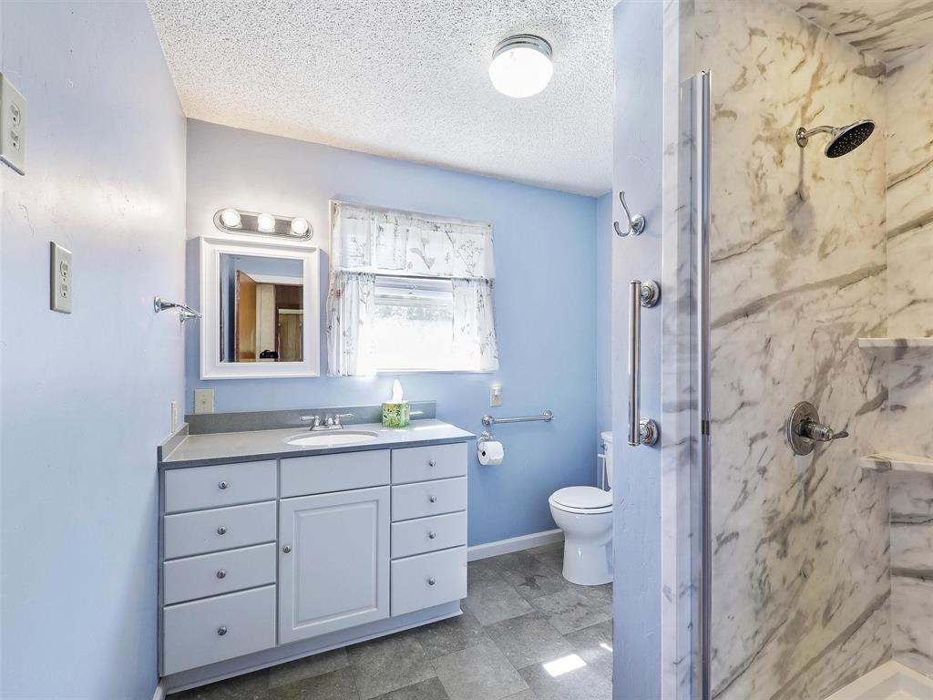 404 Selma Road Bowie, TX 76230 - Photo 13 of 21 a bathroom with a double vanity sink toilet mirror and shower