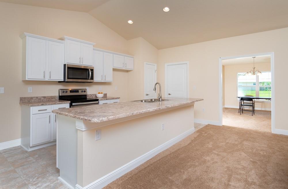 1391 Seahouse Street Sebastian, FL 32958 - Photo 8 of 18 a kitchen with granite countertop a sink a stove top oven a counter space and cabinets