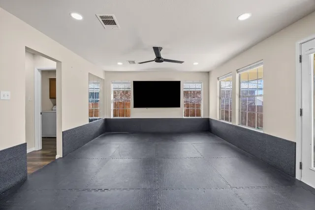 a view of a livingroom with a chandelier fan and windows