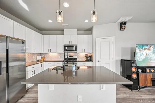 a kitchen with stainless steel appliances granite countertop a sink a stove and refrigerator
