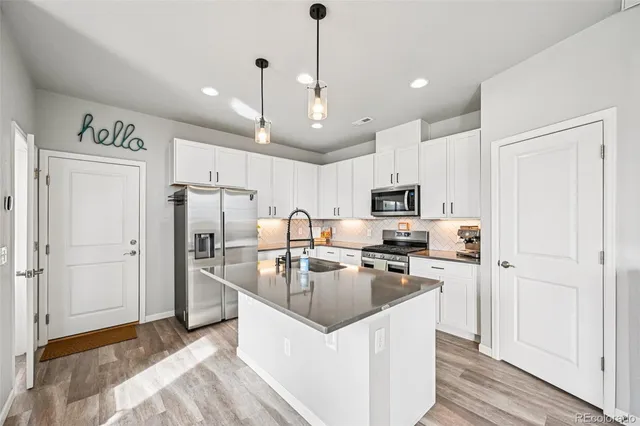 a kitchen with stainless steel appliances granite countertop a refrigerator a stove a sink and a center island