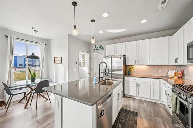 a kitchen with stainless steel appliances granite countertop a table chairs stove and white cabinets