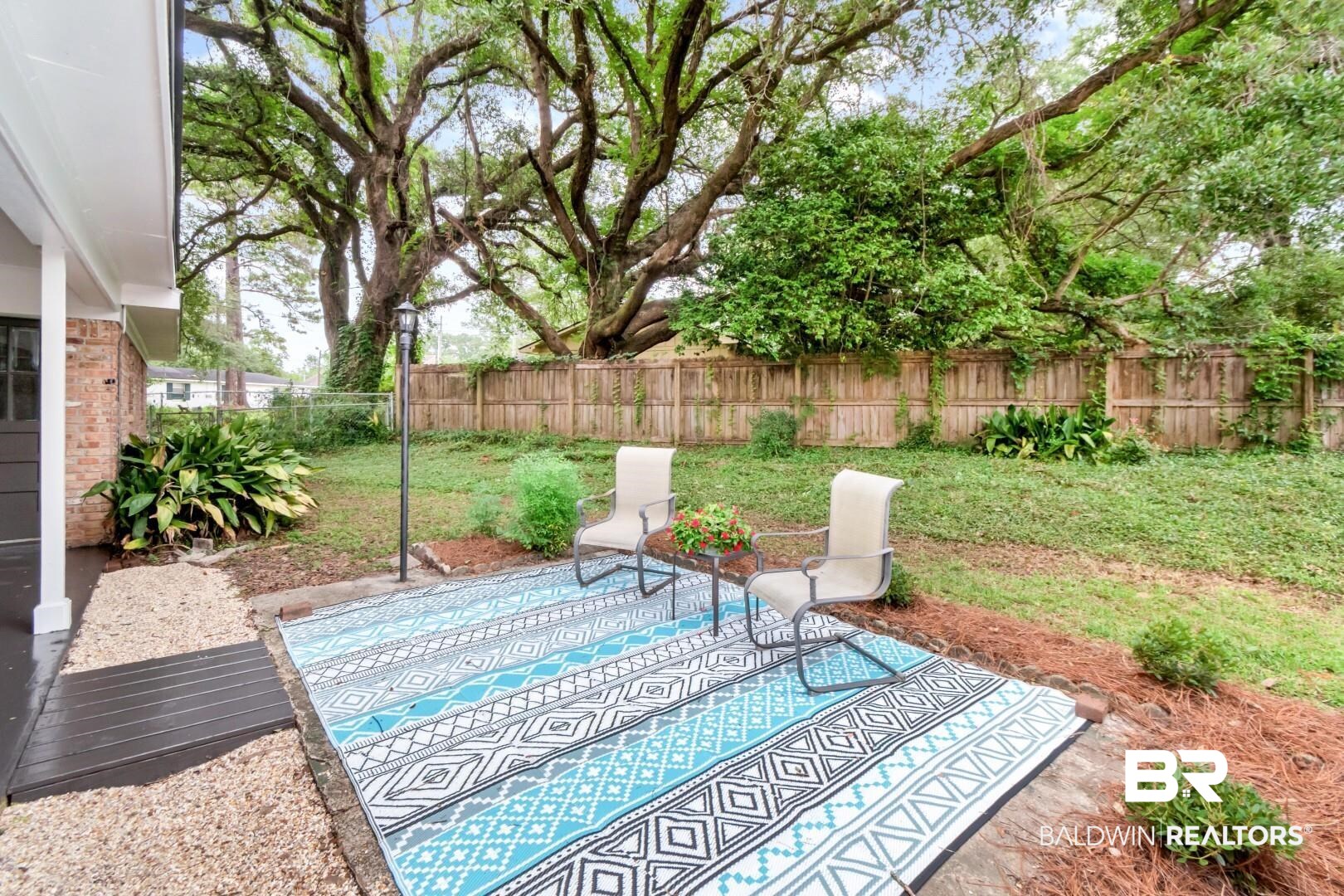 5217 Perin Road Mobile, AL 36693 - Photo 32 of 45 Expansive backyard with a wood privacy fence, mature trees, and a gravel patio area