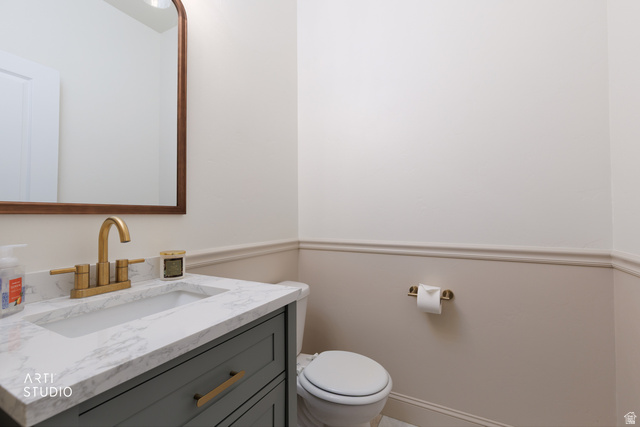 1654 South 730 West Provo, UT 84601 - Photo 13 of 33 Powder room featuring wainscoting, a gold-framed arched mirror, a vanity with a white-veined countertop, an undermount sink, and a gold-finish faucet