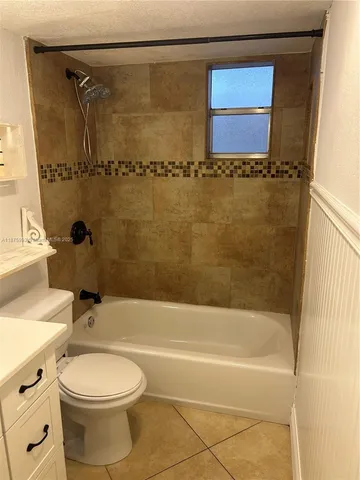 a bathroom with a granite countertop bathtub shower sink vanity and toilet