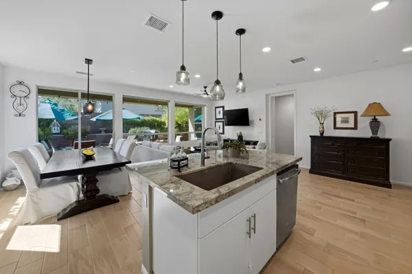 a kitchen island with stainless steel appliances granite countertop a sink a stove and a wooden floor