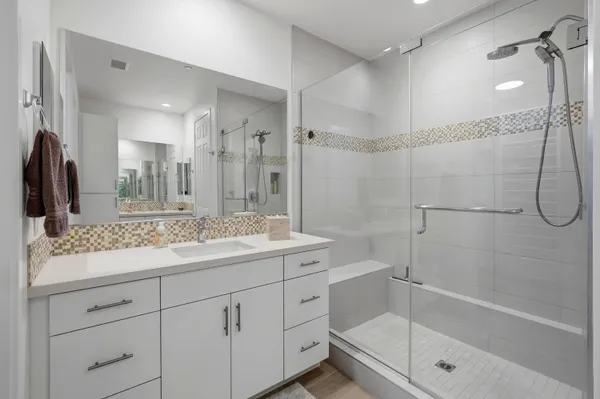 a bathroom with a granite countertop sink a mirror a shower and a bathtub