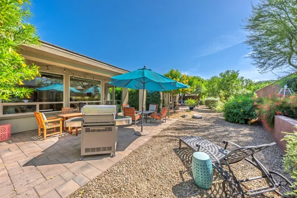 a view of patio with chairs and tables with a umbrella