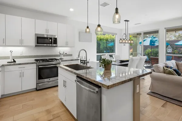 a kitchen with stainless steel appliances granite countertop a sink a stove and a wooden floors