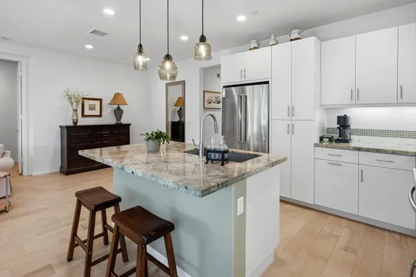 a kitchen with kitchen island granite countertop a table chairs refrigerator and microwave