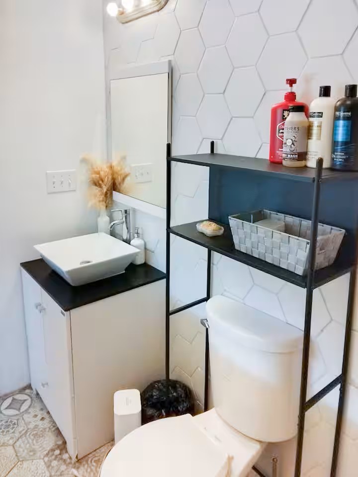 16107 Fagerquist Road Del Valle, TX 78617 - Photo 11 of 17 Crisp white hexagon tile accents this modern bathroom, featuring a sleek vessel sink and practical storage.