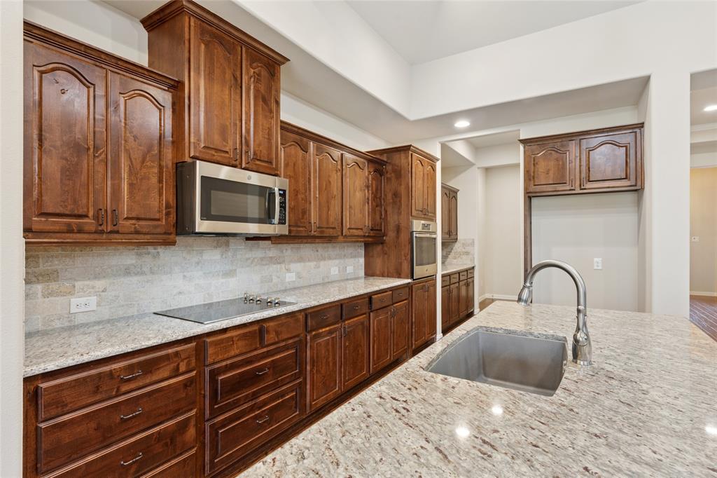 2104 Ladera Way, Unit 2104 Mansfield, TX 76063 - Photo 11 of 27 a kitchen with granite countertop a stove a sink and a microwave
