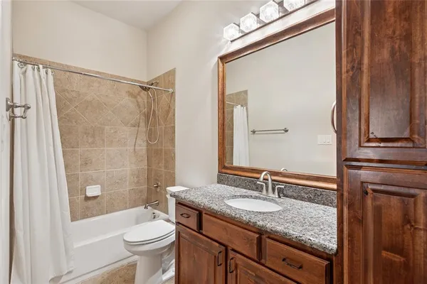 a bathroom with a granite countertop sink toilet and shower
